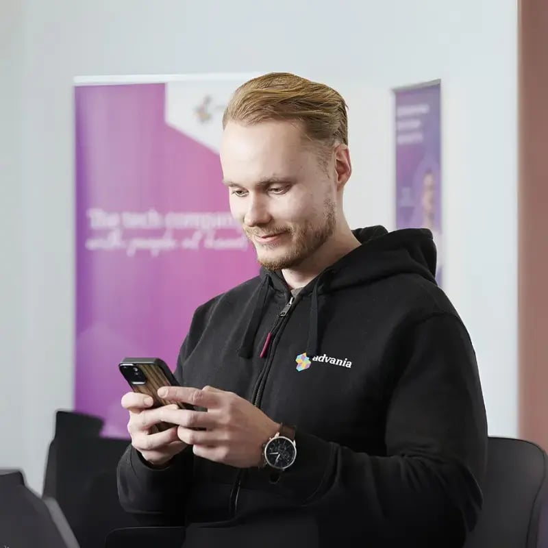Advanian asiantuntija neuvotteluhuoneessa katsomassa kännykkää